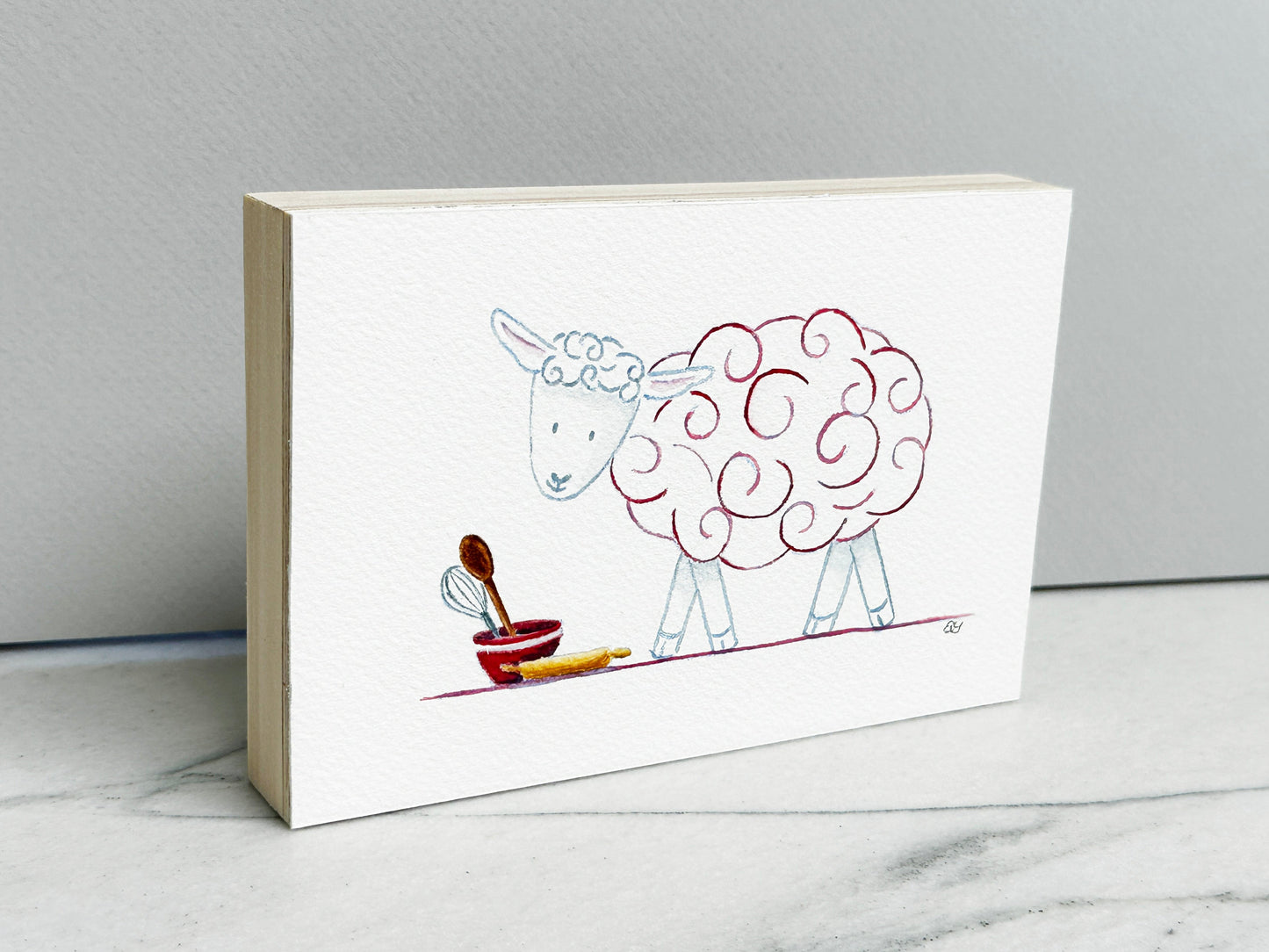 Molly the Sheep, an original watercolor painting of a sheep with raspberry pink curls and baking tools, mounted on a cradled wood panel, side view